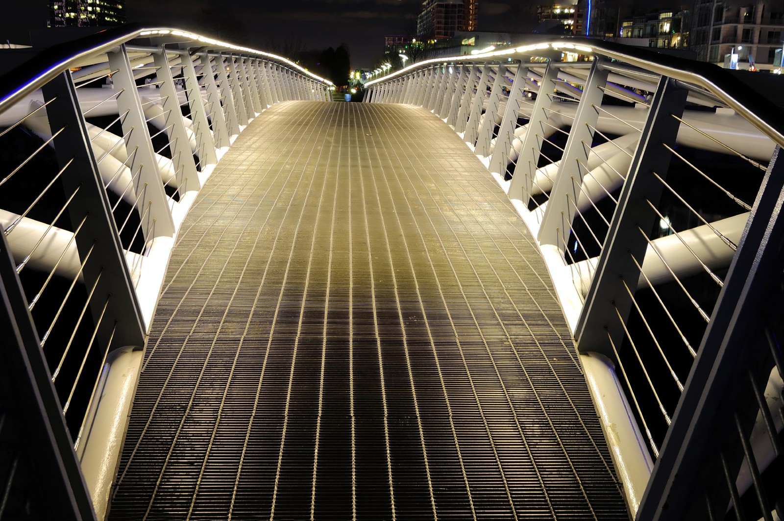 A pedestrian bridge lit from underneath handrails
