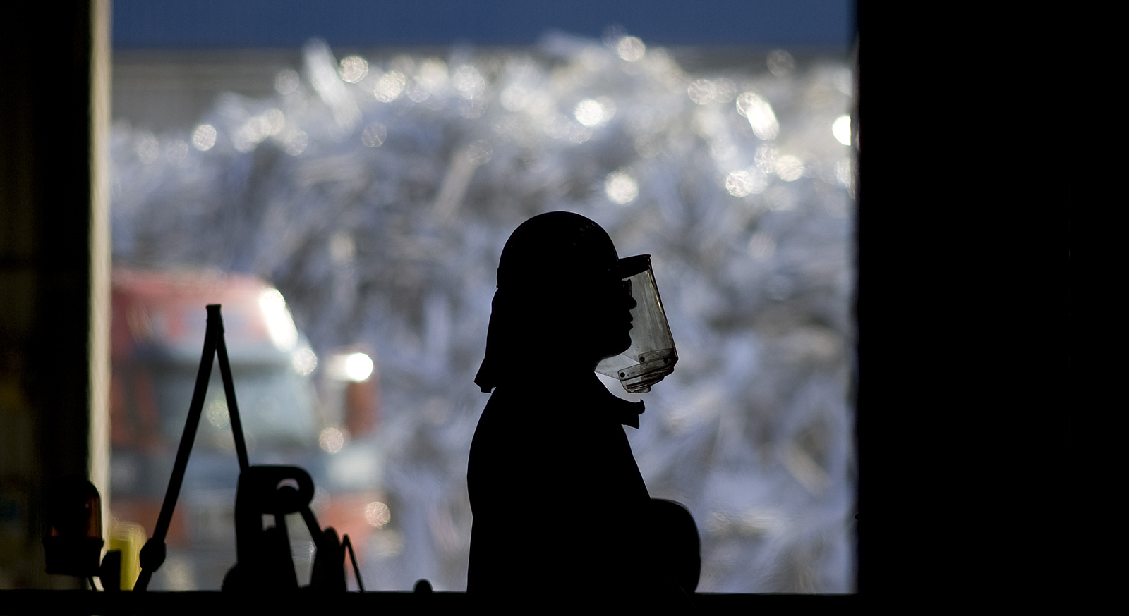 worker in front of a huge pile of aluminium