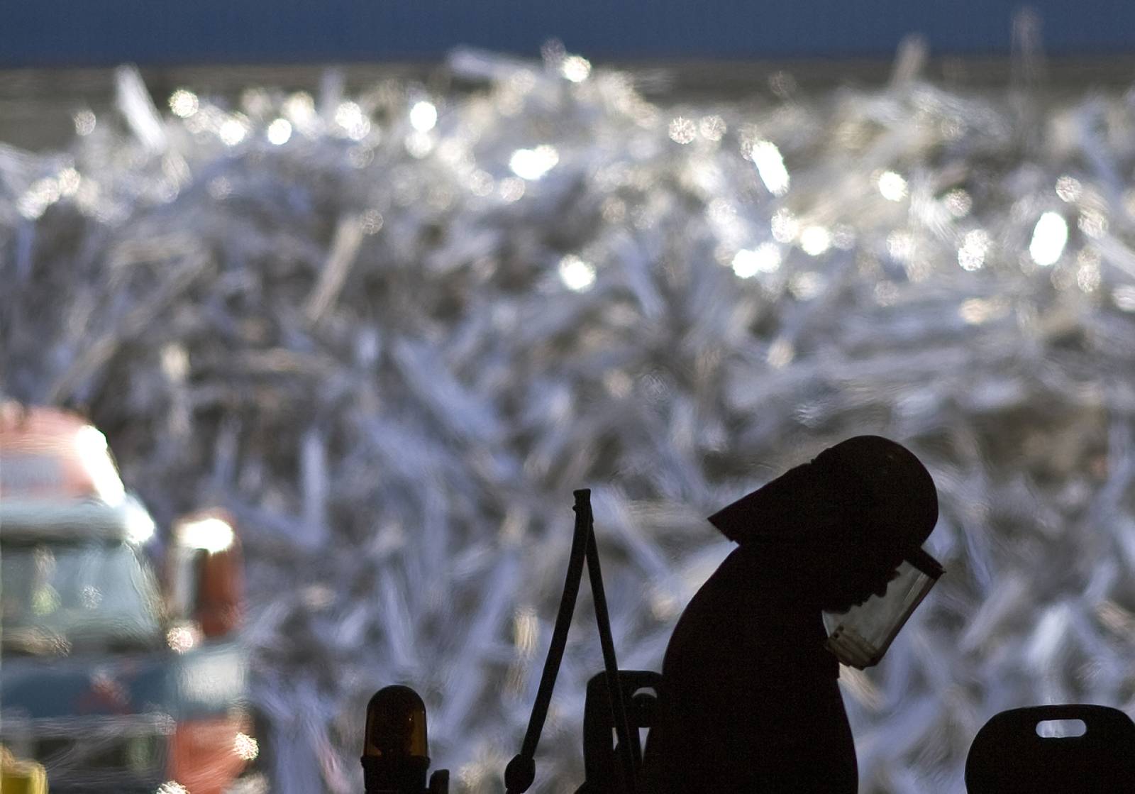 Person in protective gear in front of heap of scrap metal