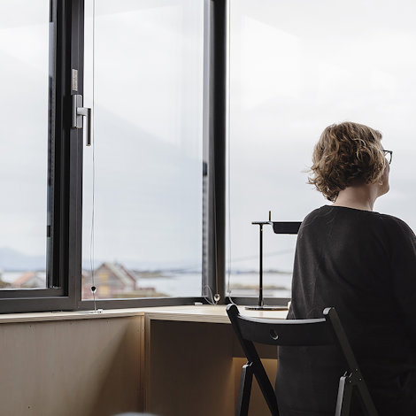 woman at desk in front of large windows looking out over coastline view