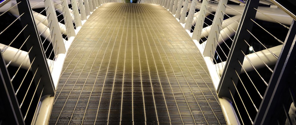 A pedestrian bridge lit from underneath handrails