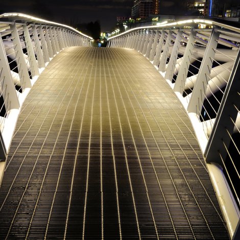 A pedestrian bridge lit from underneath handrails