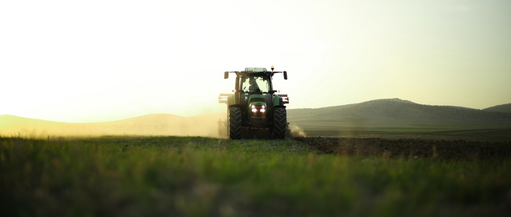 A harvester in a field at sunset